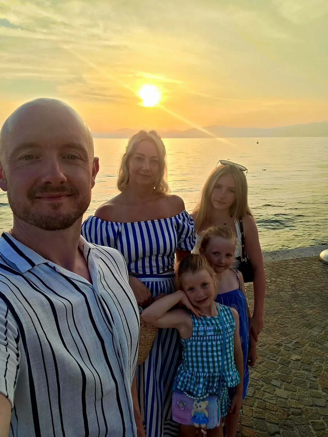 Carl Barry with a woman and three girls on a waterfront at sunset