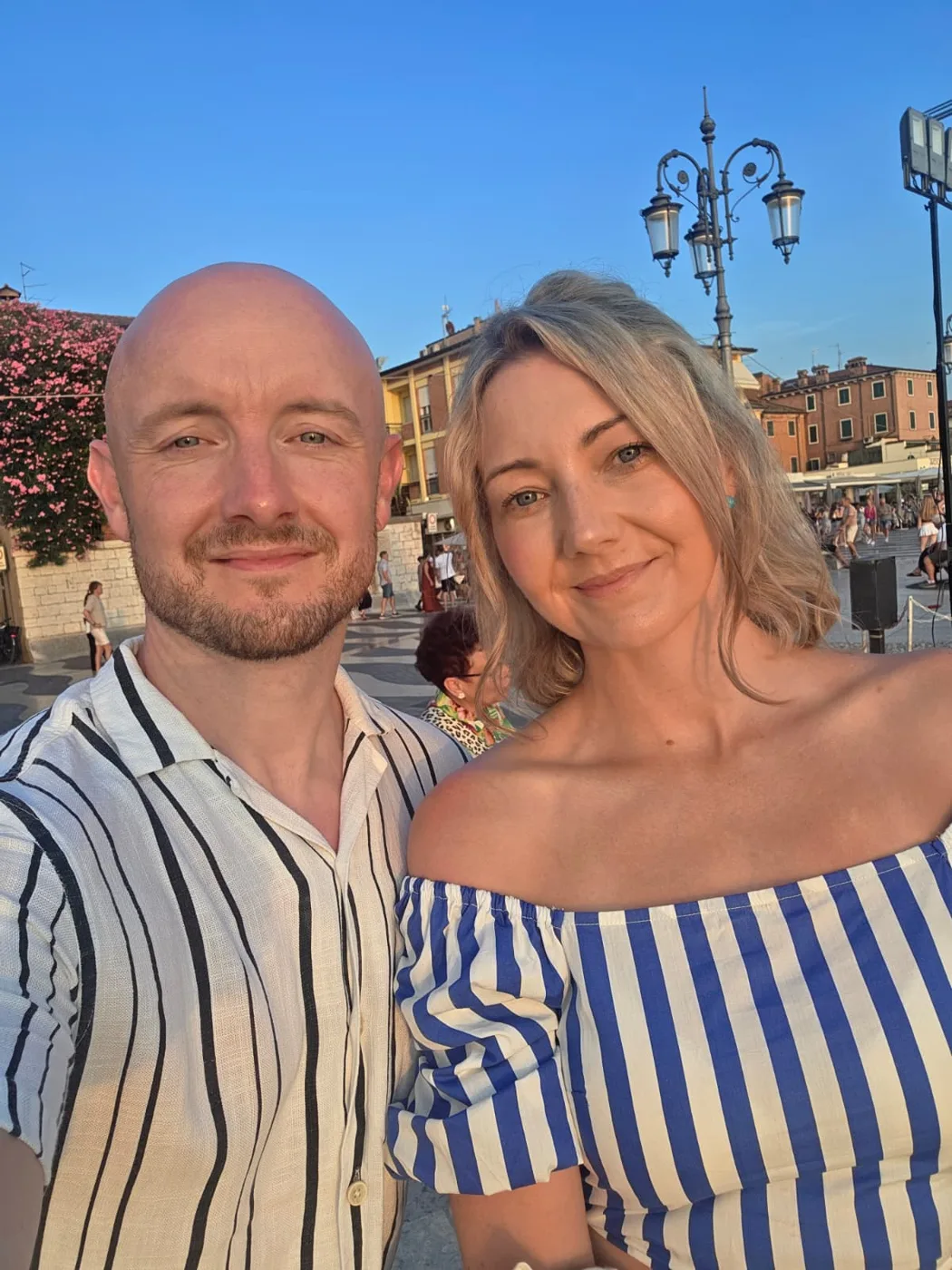 Carl Barry and a woman smiling in a town square on a sunny evening