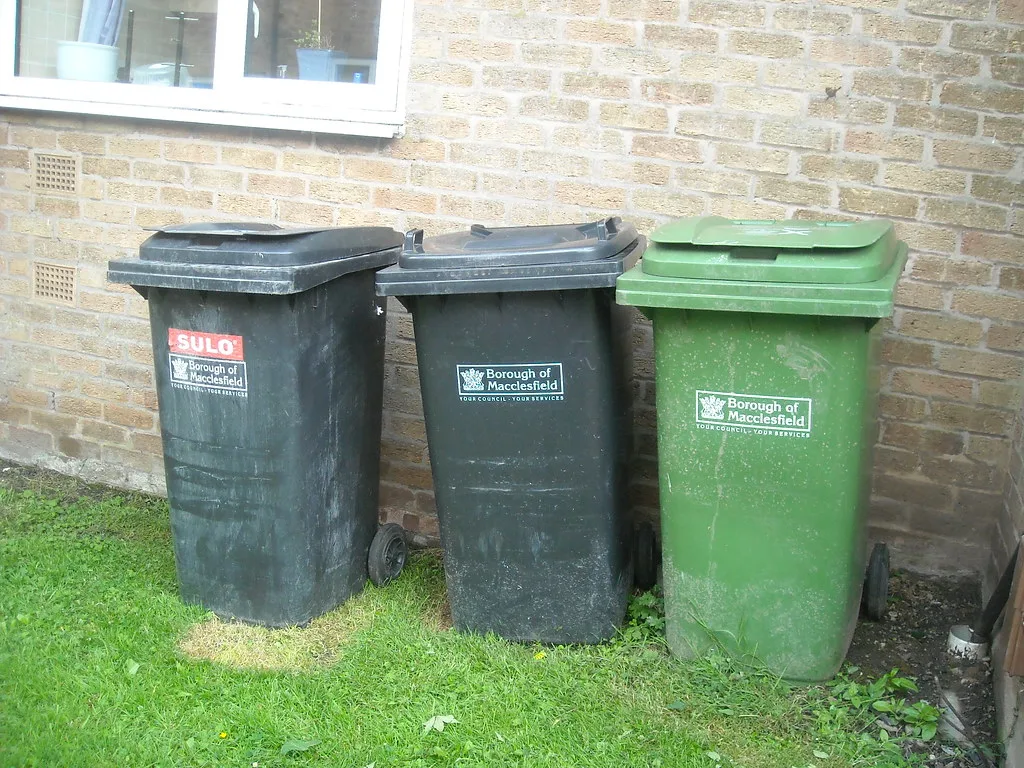 Wheelie bins still carrying the old Borough of Macclesfield crest, from before Cheshire East took over in 2009. The photo does not show the new food waste caddies.